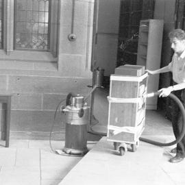 Vacuuming books outside the Old Post Office, before move to Fisher Library, 1962
