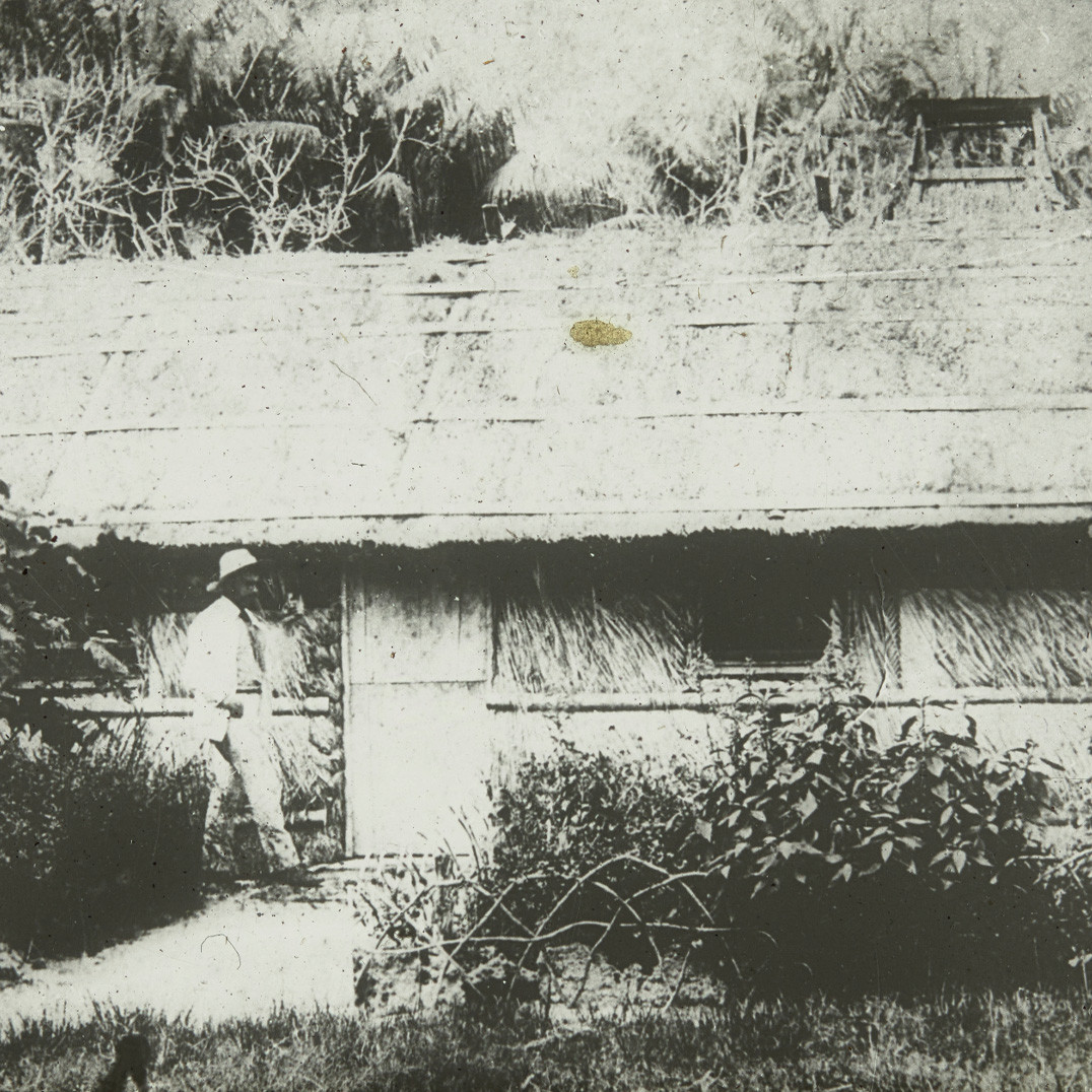 Person in front of palm thatched cottage, Lord Howe Island